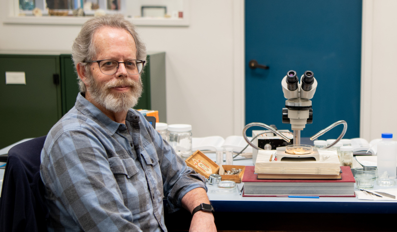 A smiling scientist next to a microscope