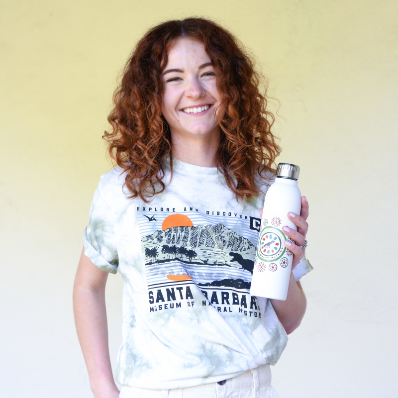 Woman wearing Museum branded shirt holding a reusable water bottle.